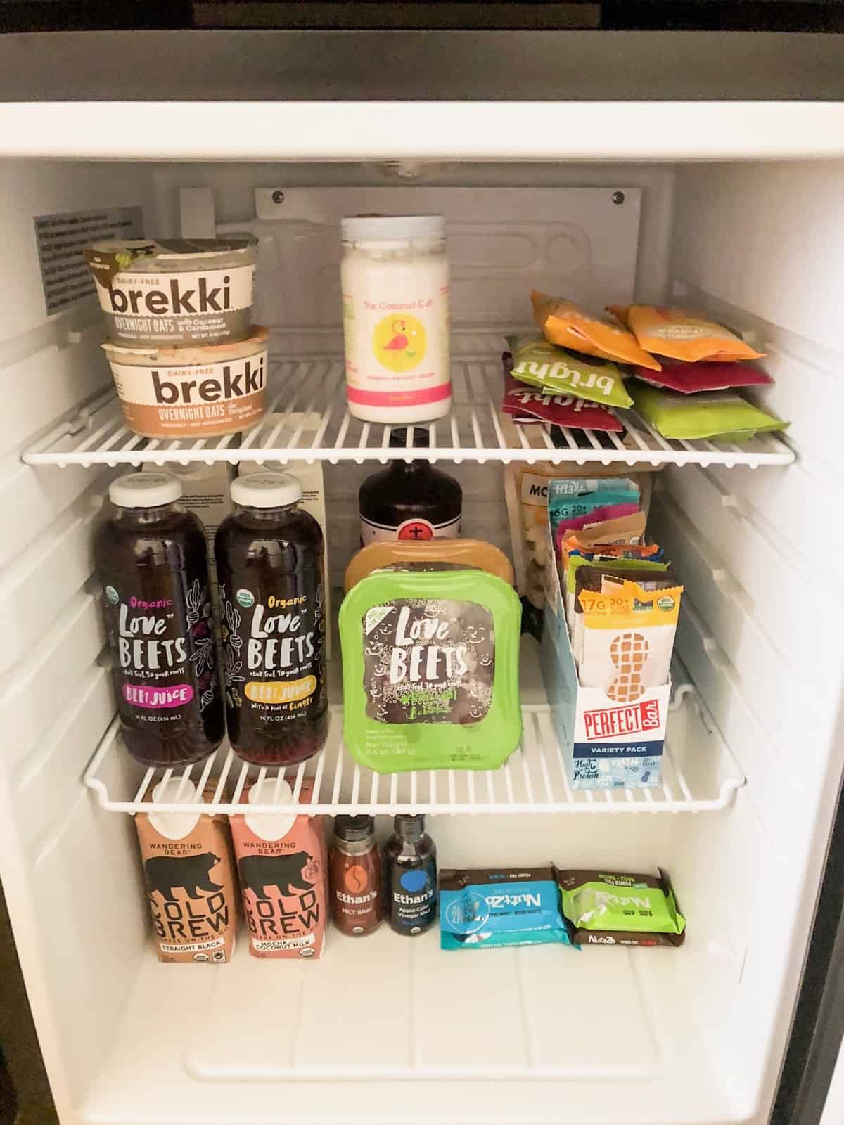 Small mini fridge stocked with a lot of snacks