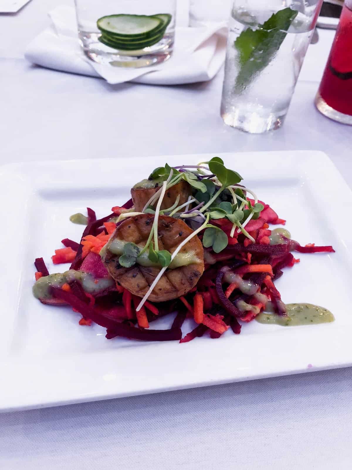Plate of king oyster mushrooms with a beet and carrot slaw topped with micro greens