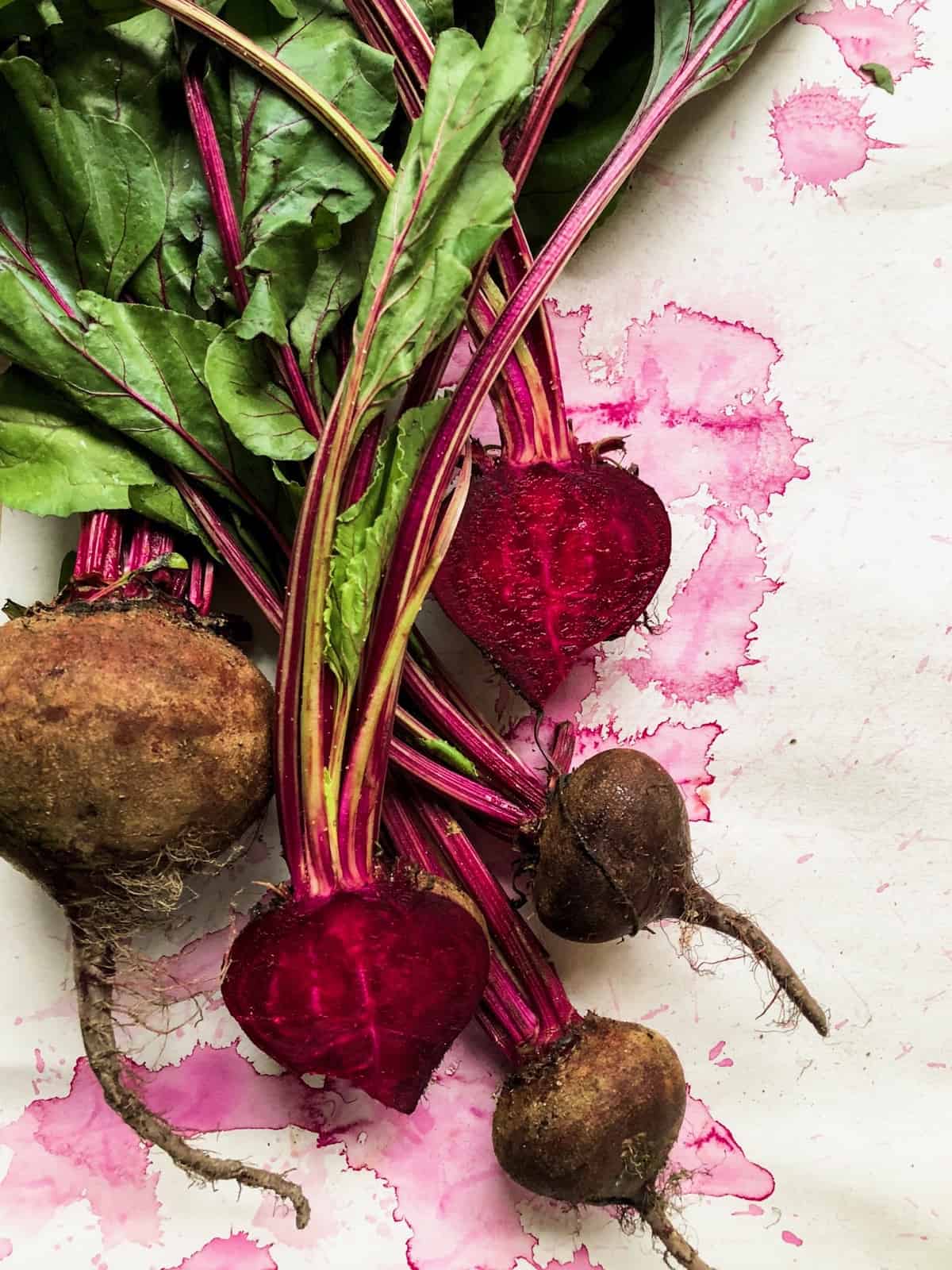 White paper with a bushel of beets on it, with some cut open exposing their flesh