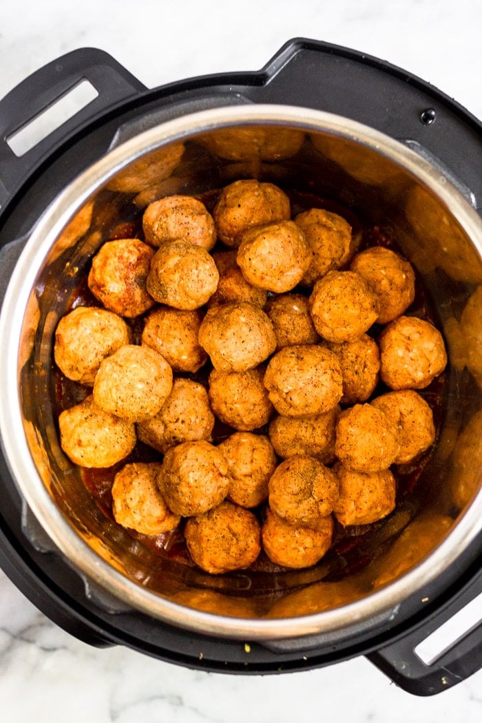 Instant pot filled with raw chicken meatballs piled on top of each other.