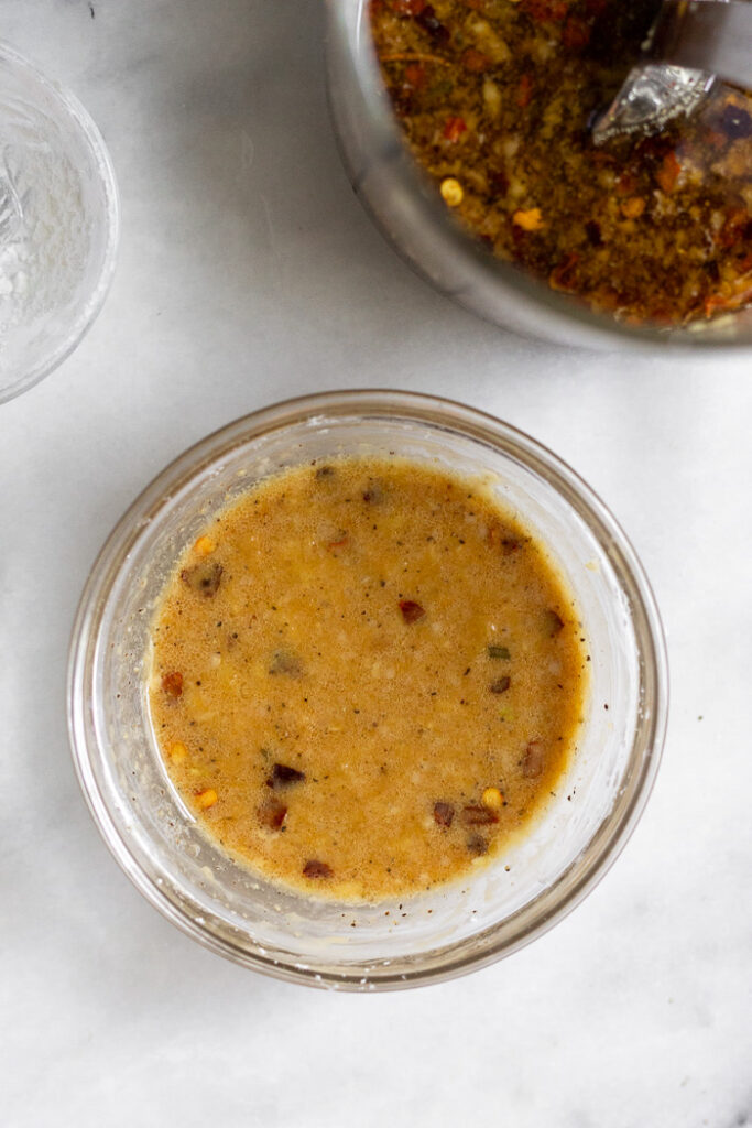 Small bowl of beef broccoli sauce with flour mixed into it. Next to it a larger cup of more sauce.