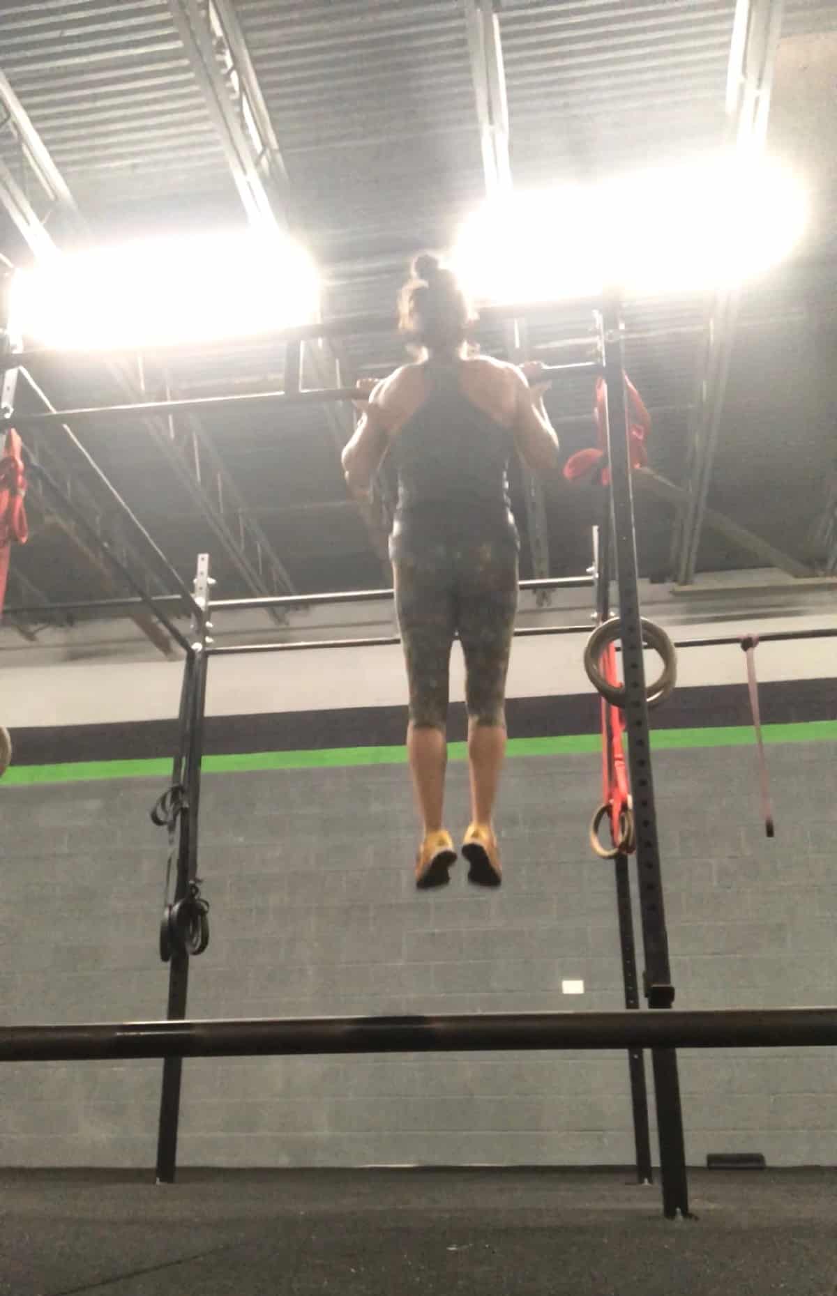 Girl with her chin over the bar doing a strict chin up