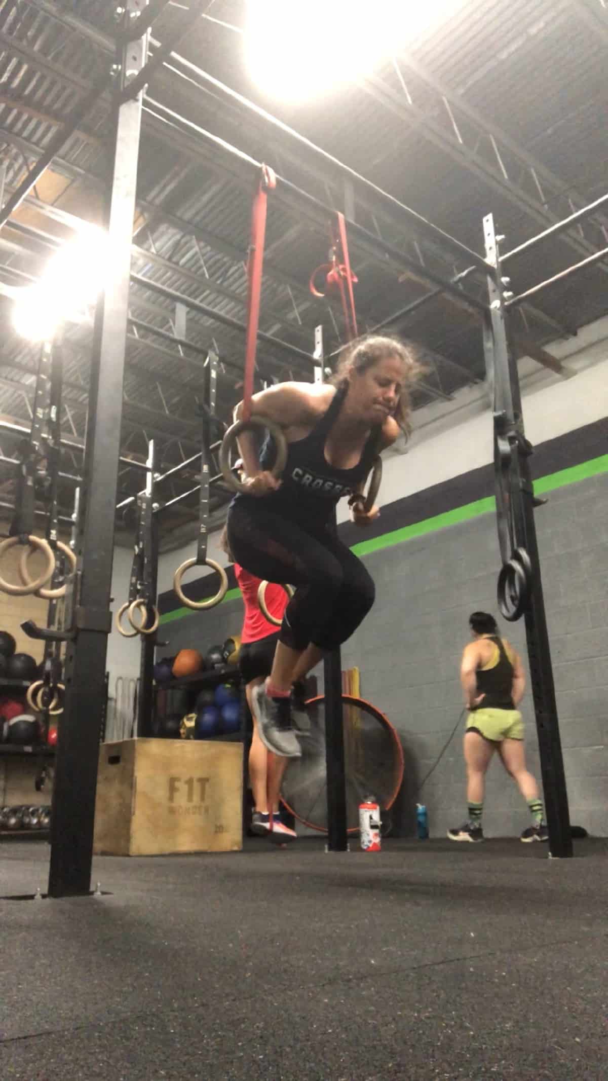 Girl in a CrossFit gym doing a ring dip