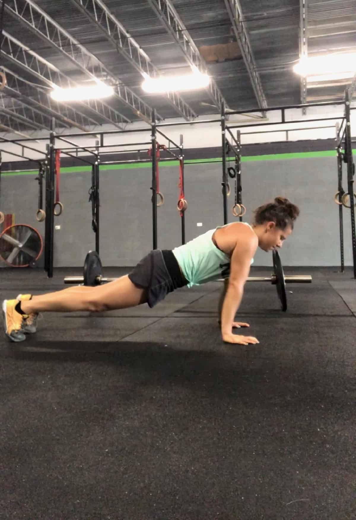 Girl on your feet and hands in a high plank position doing a push-up