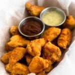Basket of Whole30 and paleo popcorn chicken with two dipping sauces, one of BBQ and one of ranch