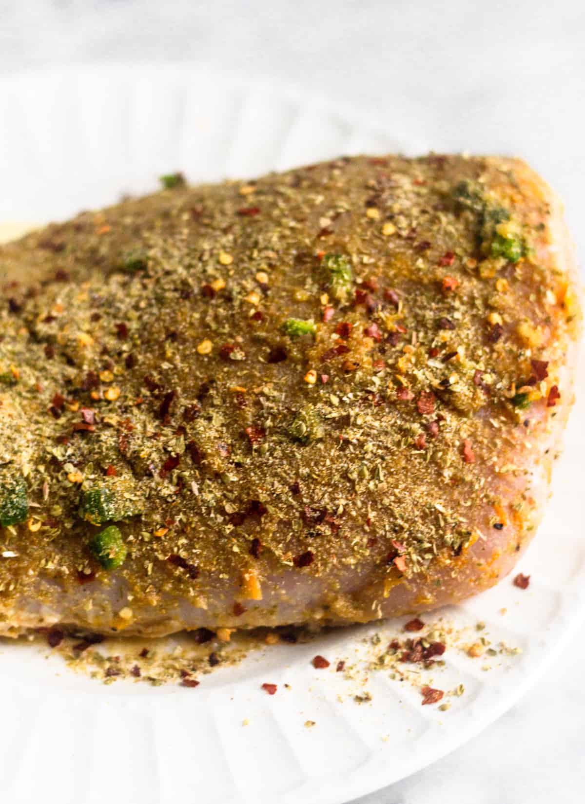 A raw turkey breast with some seasonings rubbed all over it