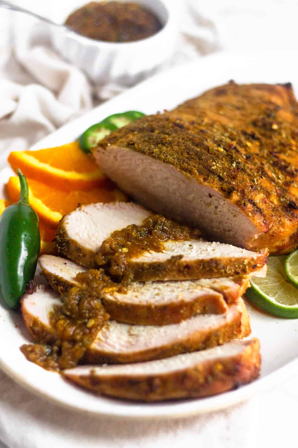 A platter of citrus grilled turkey breast with a spicy citrus sauce overtop the cut pieces