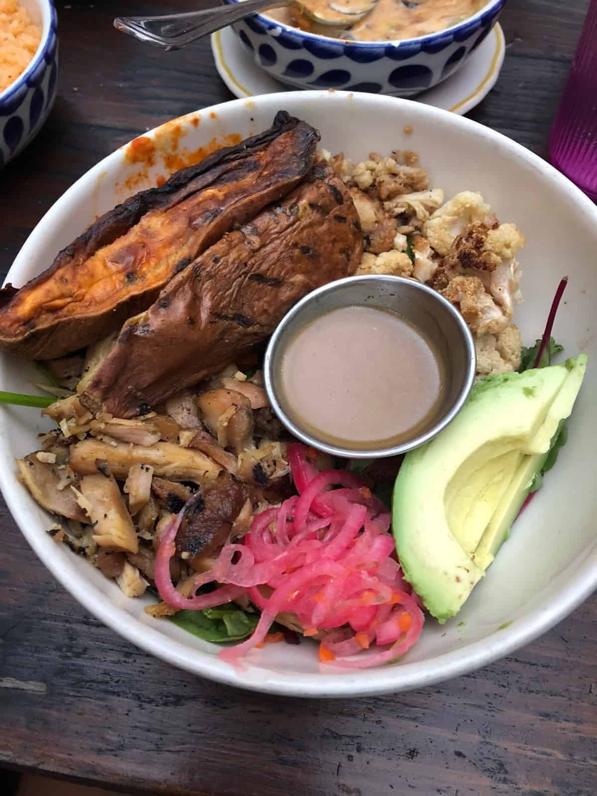 Power bowl from Fresca's in Austin, TX. Filled with cauliflower, sweet potato, chicken, pickled onions, avocado, and dressing