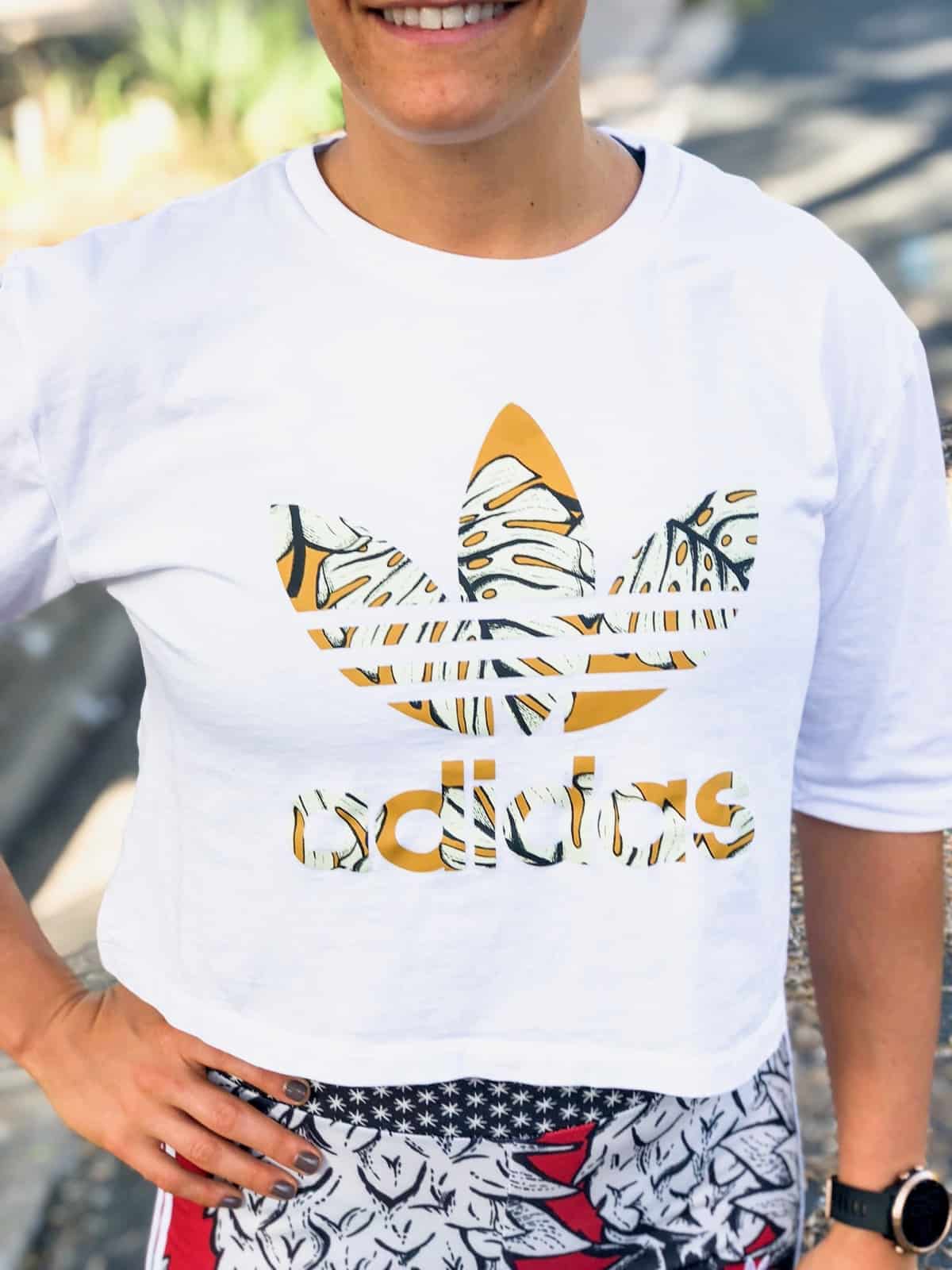 Girl wearing a white Adidas crop top. The picture is only showing her upper body.