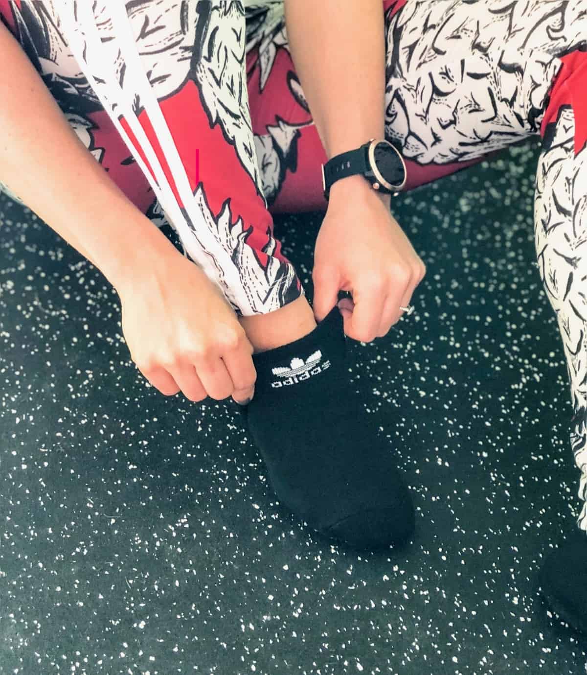 A girl putting on black no show Adidas socks