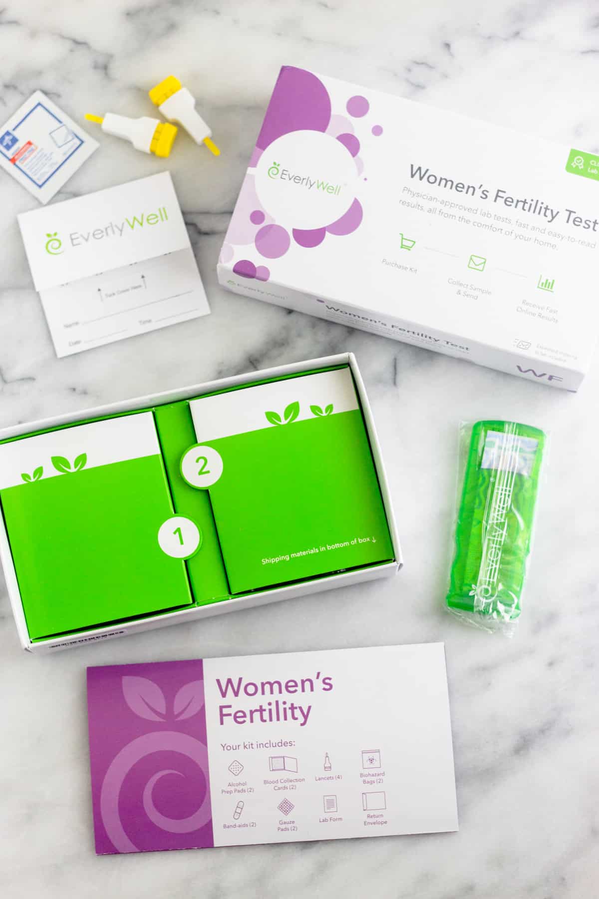 Inside of the package of a Women's Fertility Testing at Home with EverlyWell. Shows the instructions, bandaids, finger prickers, and a cleaning pad.
