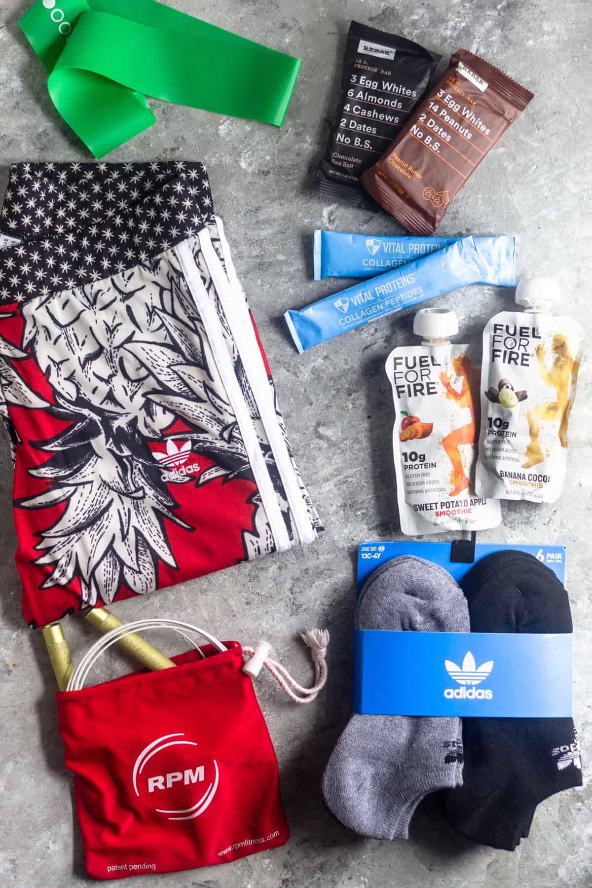 A bunch of items in a holiday gift guide for active women laid out on a grey surface. The items consist of leggings, snacks, socks, a jump rope, and a resistance band.