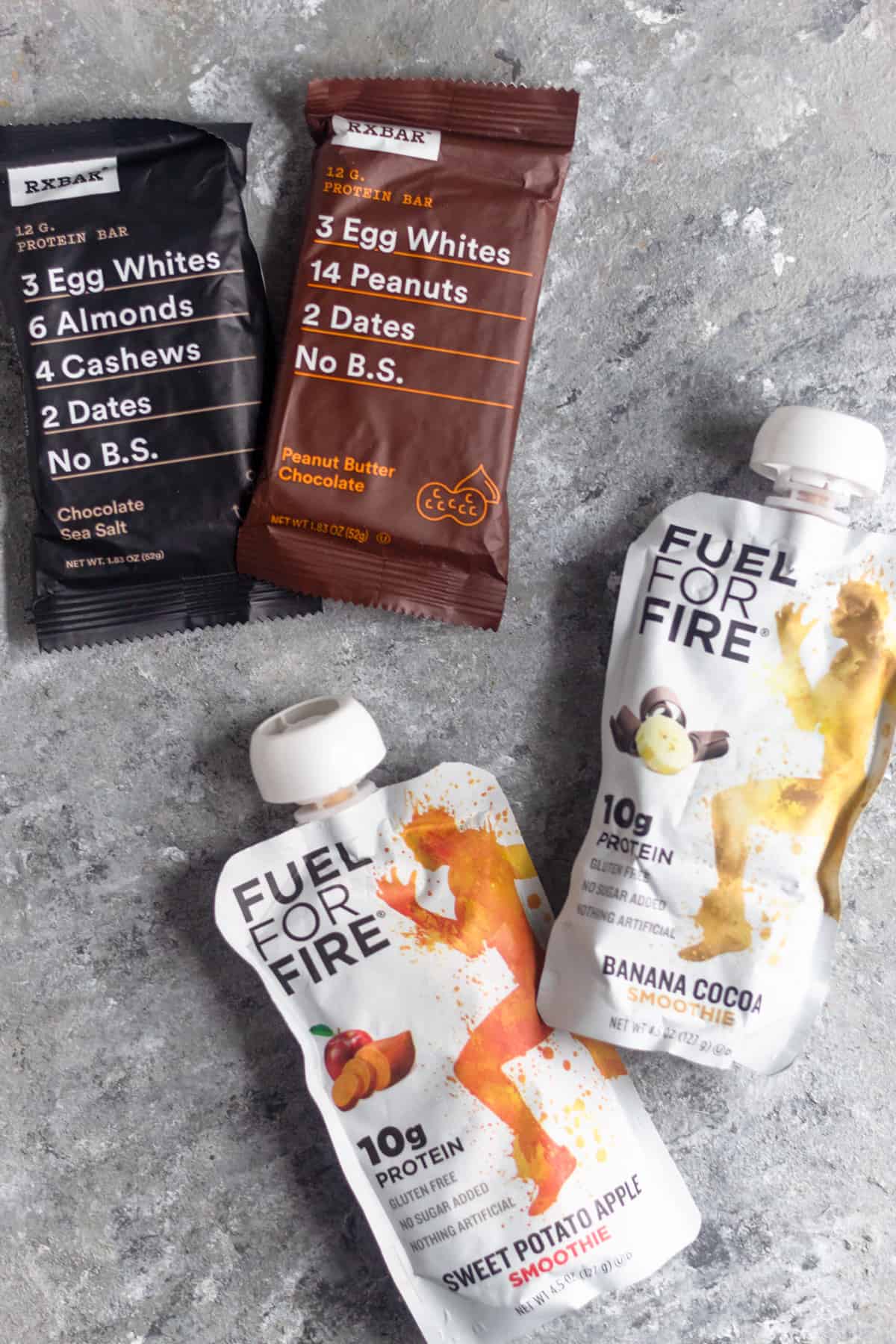 Two RXbars and two Fuel for Fire packets on a grey surface