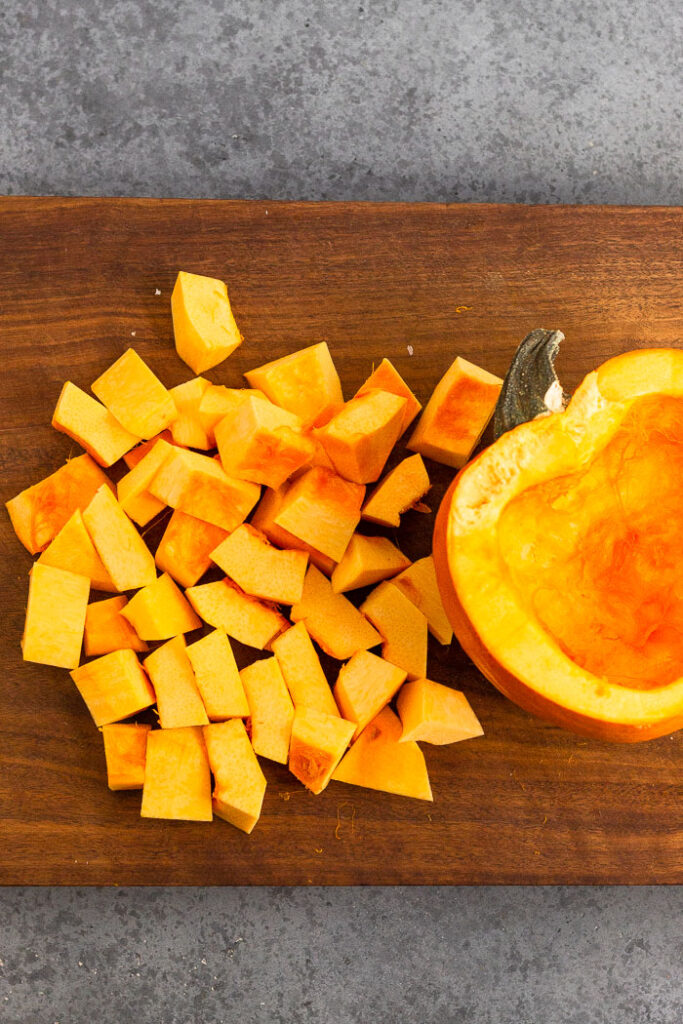 Half a sugar pumpkin roughly chopped with the other half intact next to it.