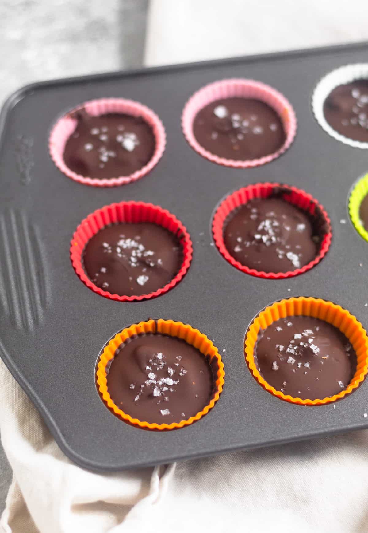 Mini muffin tin tray with pumpkin pie chocolate cups sprinkled with sea salt in them