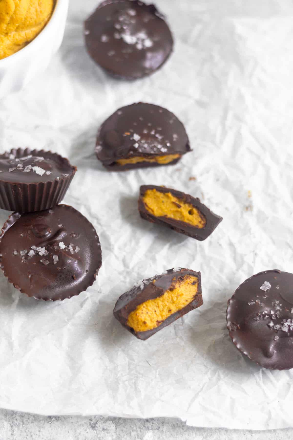 Pumpkin pie chocolate cups on parchment paper. Some are whole and some are cut open laying on their sides