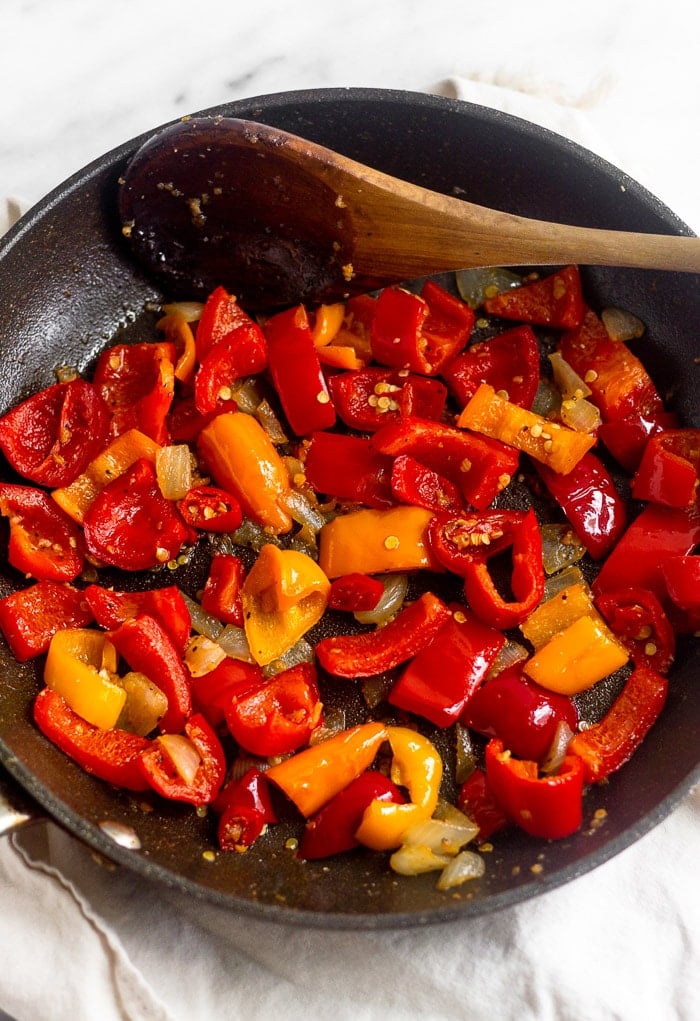 Medium skillet with sautéed peppers, onion, and garlic in it.