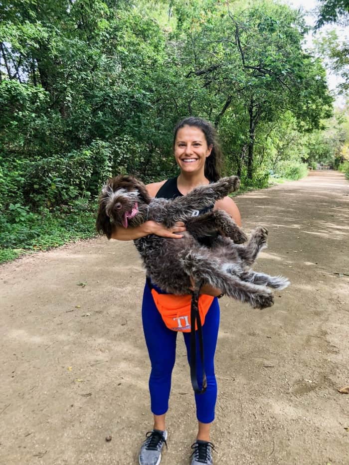 Girl in workout clothes on a trail holding her puppy