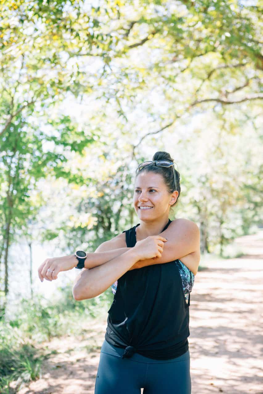 Girl stretching her arms outside on a trail by the water