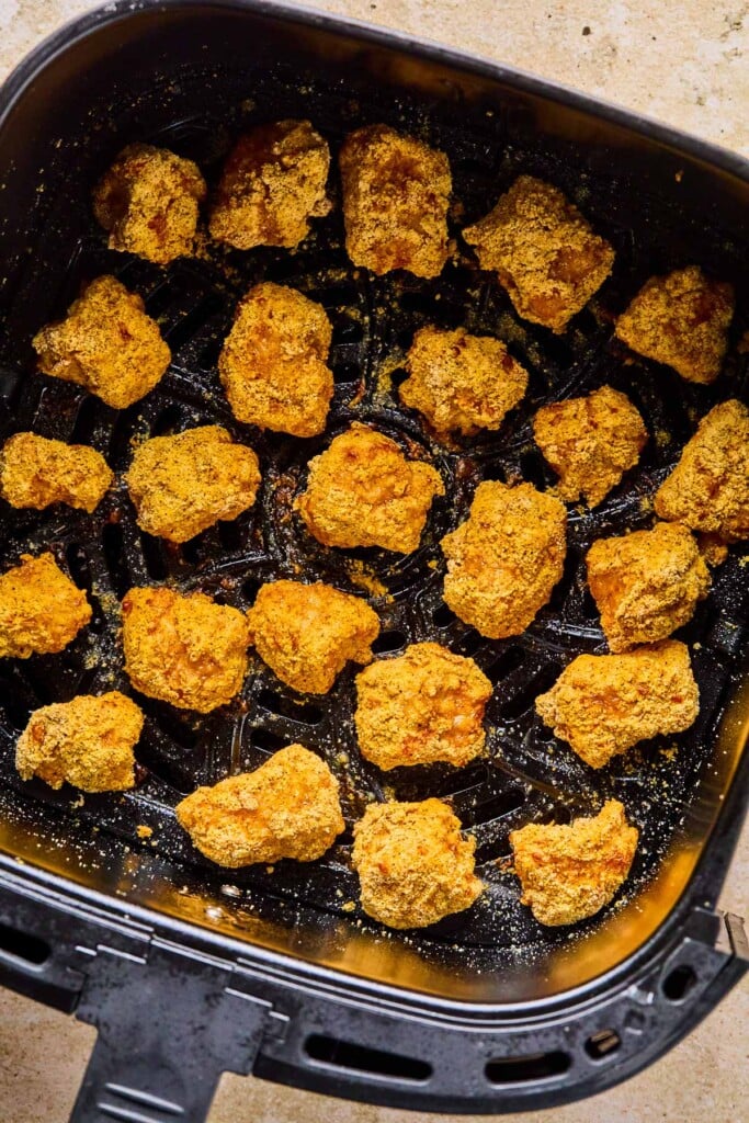 Overhead shot of boneless buffalo wings in an air fryer basket.