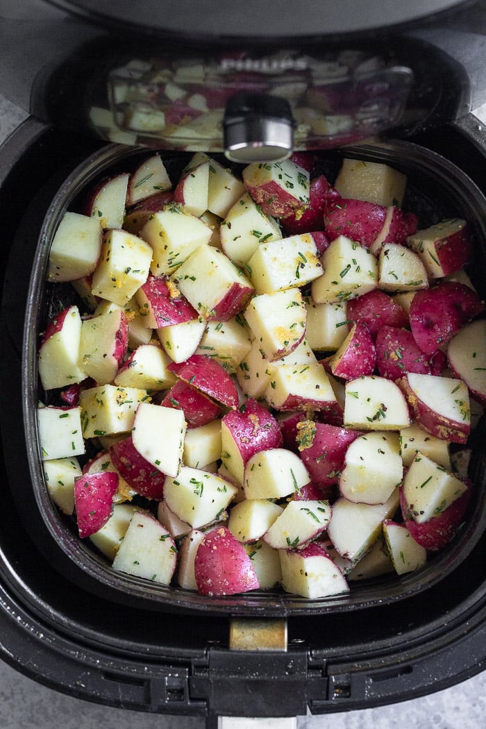 Diced raw potatoes in an air fryer basket.