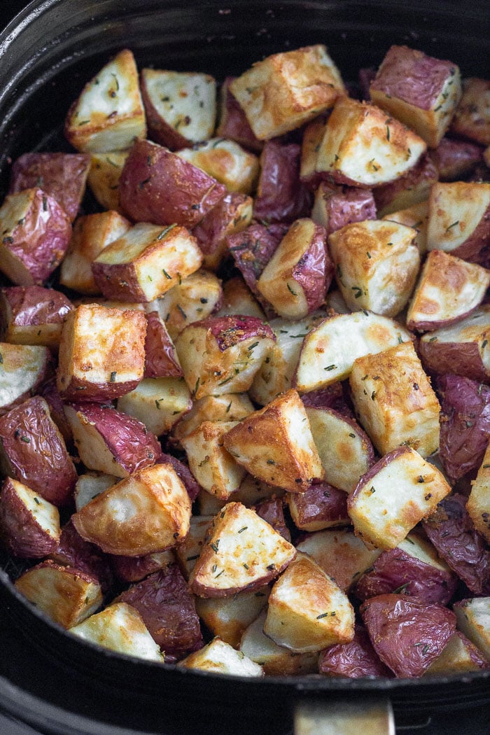Air fryer basket filled with crispy rosemary potatoes.
