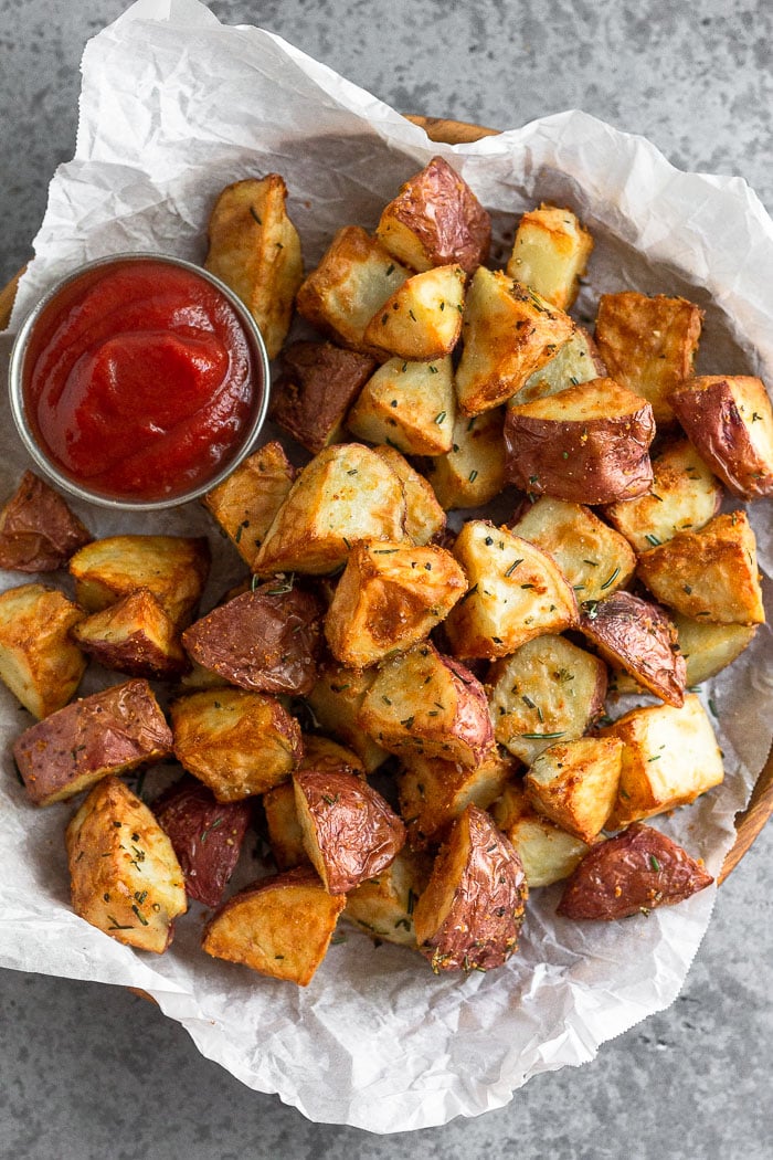 Plate of rosemary red potatoes with a ramekin of ketchup.