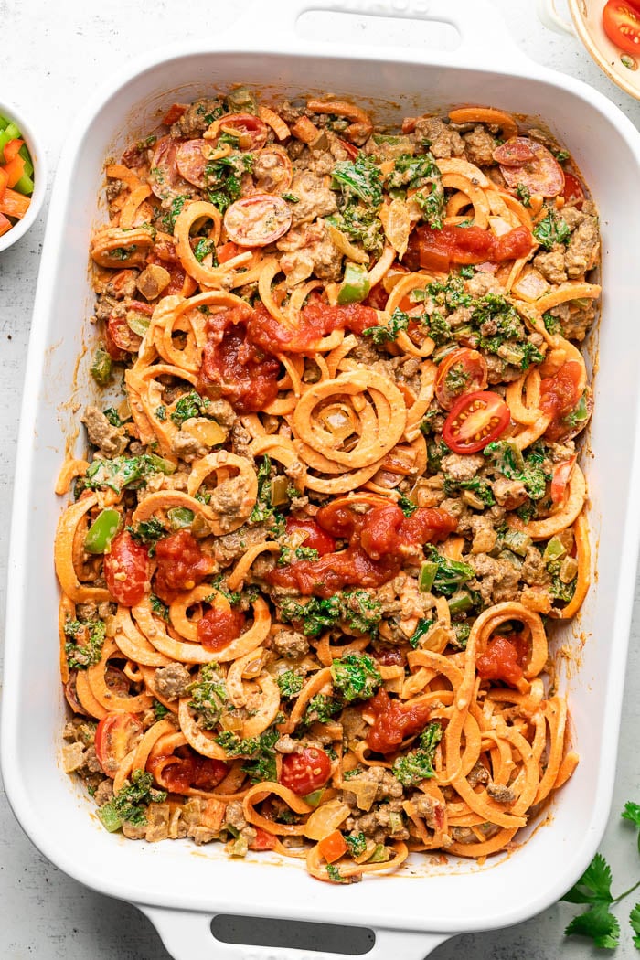 Beef taco casserole with sweet potato noodles in a large pan before it is baked.