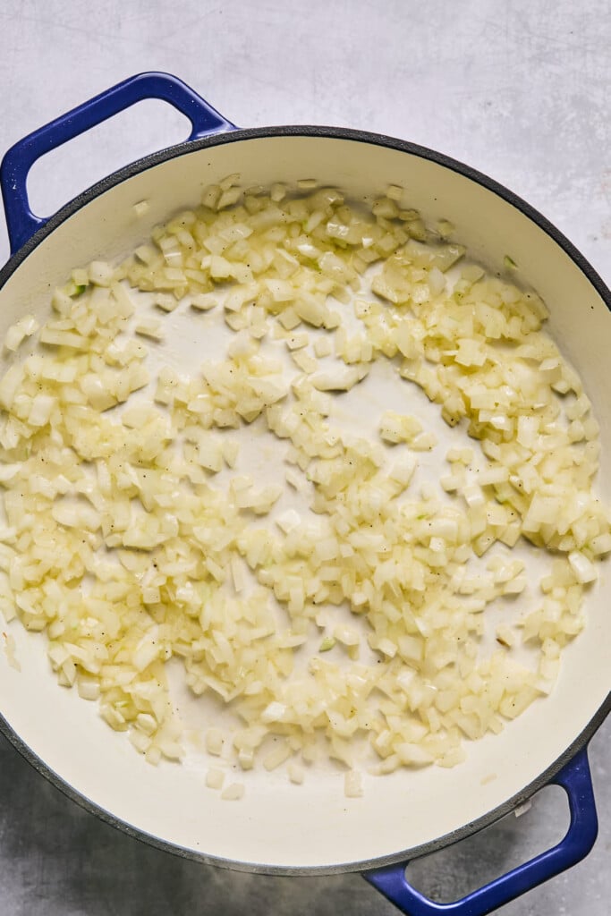 Large enameled pan filled with sautéed onions.