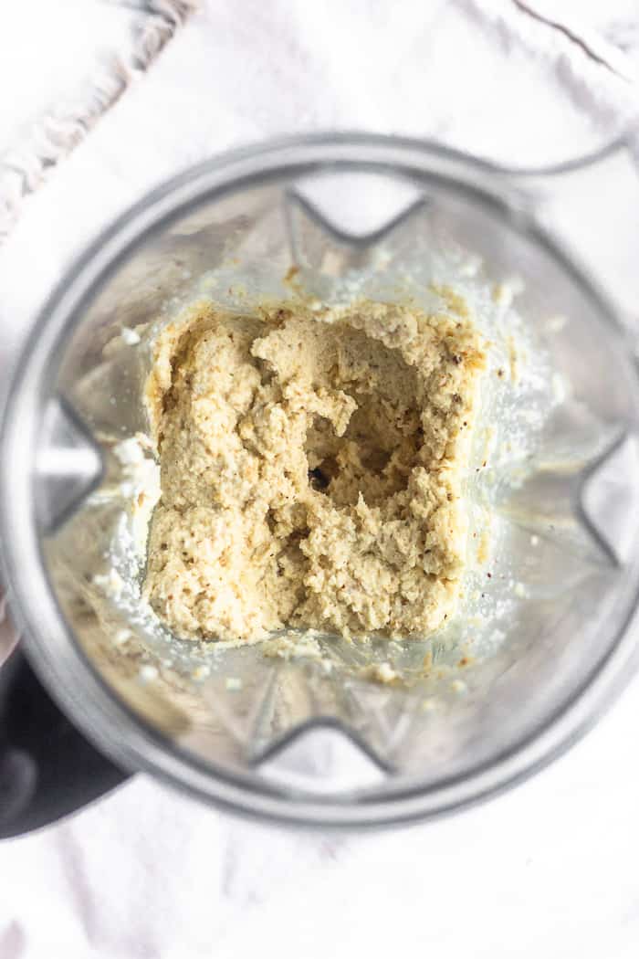 A blender filled with paleo roasted cauliflower hummus before it be blended to a smoother consistency.
