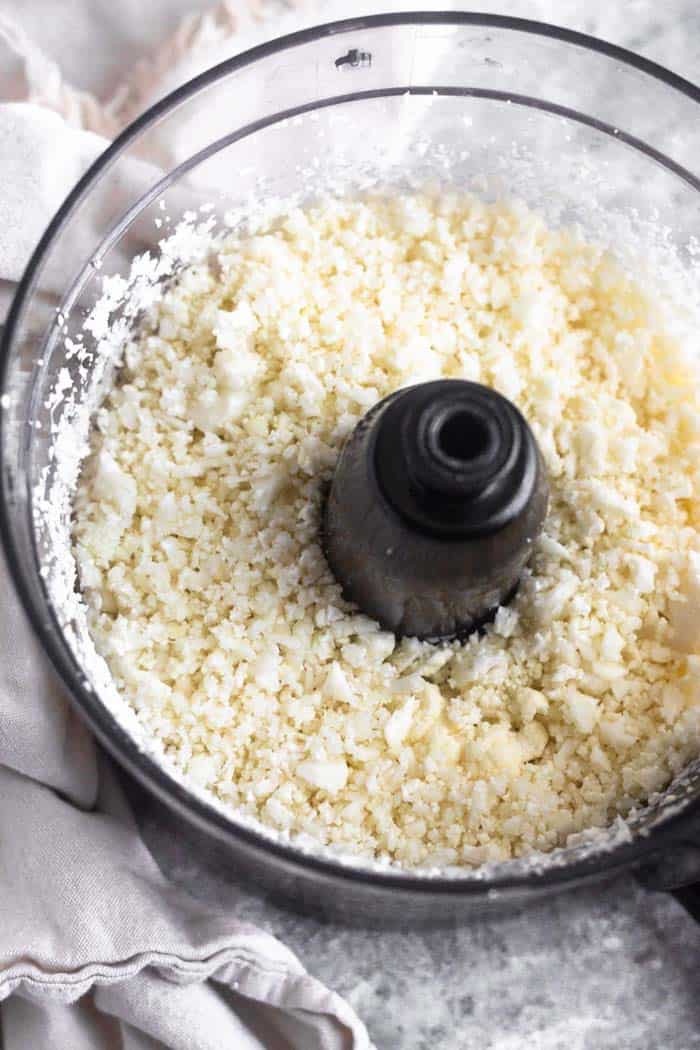 Cauliflower rice in the bowl of a food processor that had just been processed into rice.