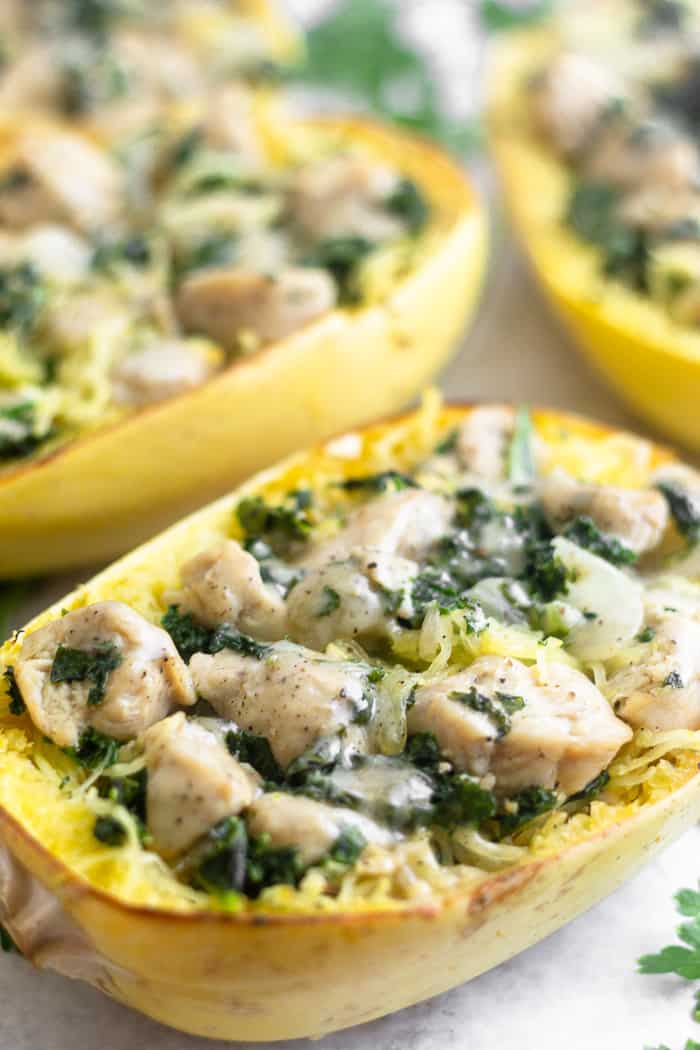 A sheet filled with chicken caesar spaghetti squash boats topped with fresh chopped parsley.