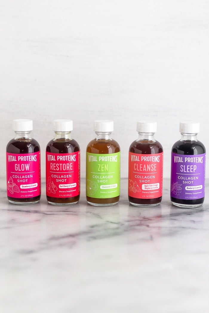 5 different flavors of collagen shots all lined up on a white counter.
