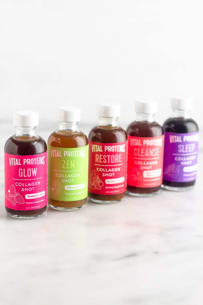 Five different flavors of collagen shits in a diagonal line on a white counter top.
