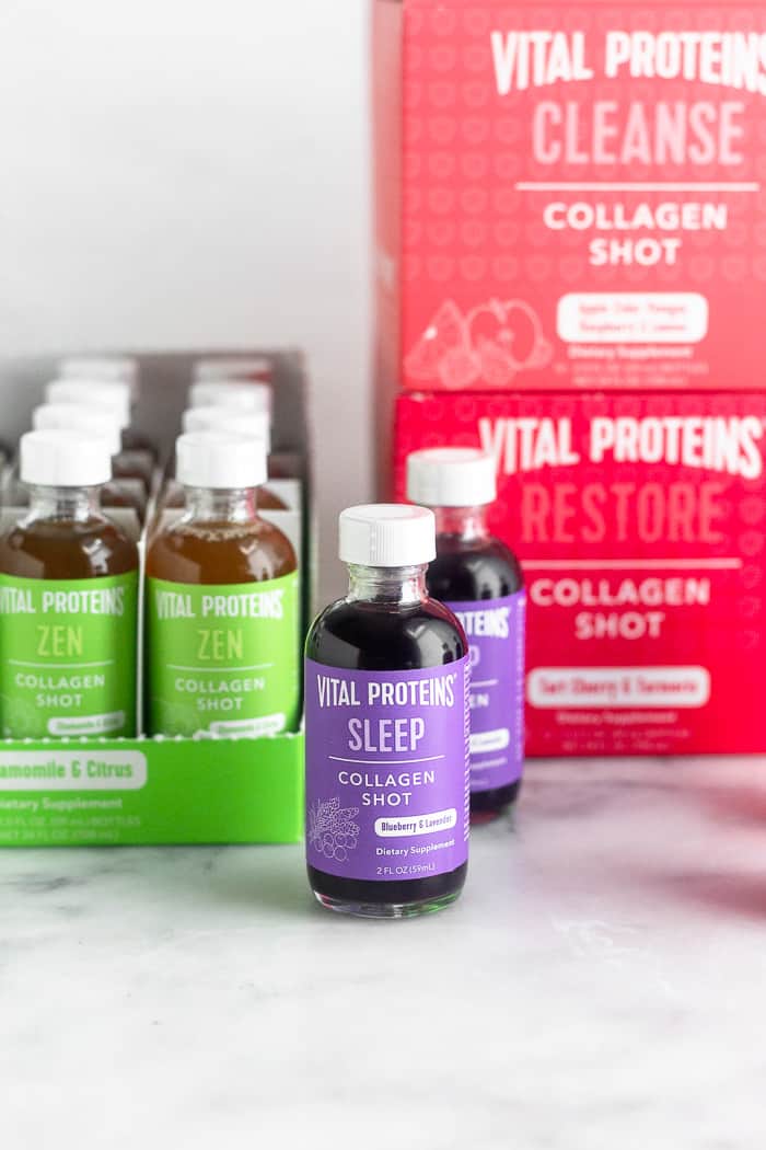 Two bottles of sleep collagen shots. Behind them are 2 boxes of different flavors and next to them is another box that is opened of another flavor.