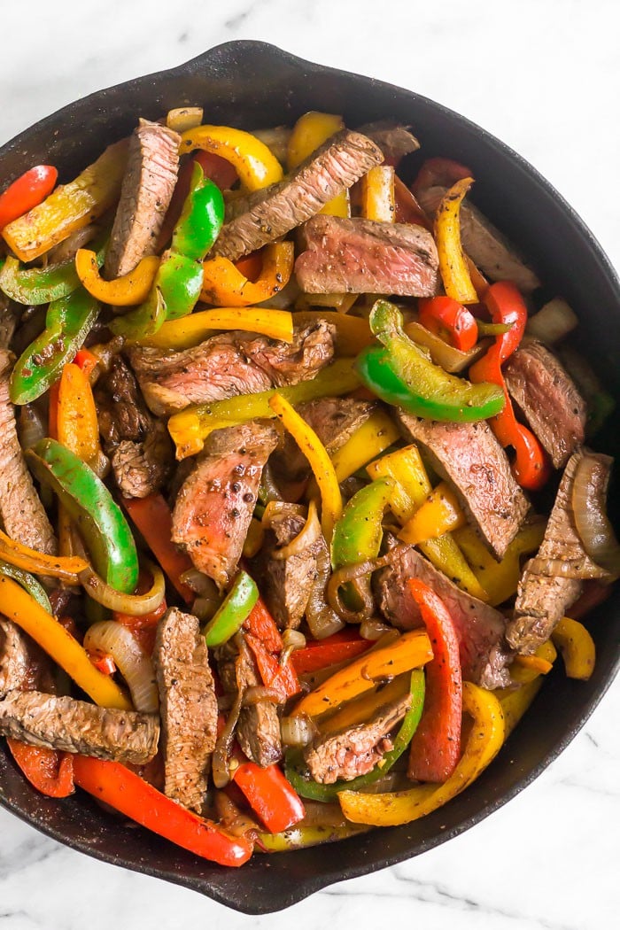 Cast iron filled with steak fajitas.