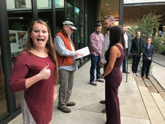 Couple running through a run through the day before their wedding ceremony. The maid of honor is giving a thumbs up.