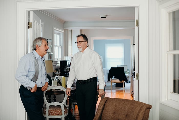 Two older gentlemen getting ready for a wedding.