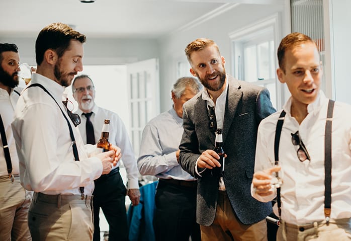 A group of guys, including the groom, getting ready for a wedding with beers in their hand.