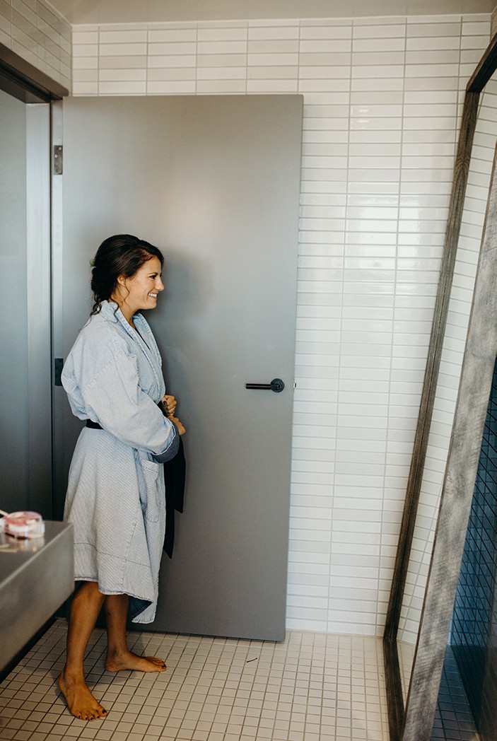 A woman getting ready on her wedding day wearing a blue robe.
