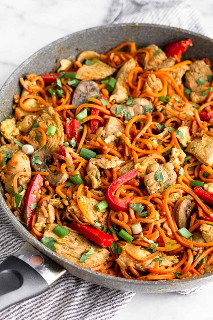 Large sauté pan filled with pad thai with chicken using sweet potato noodles.
