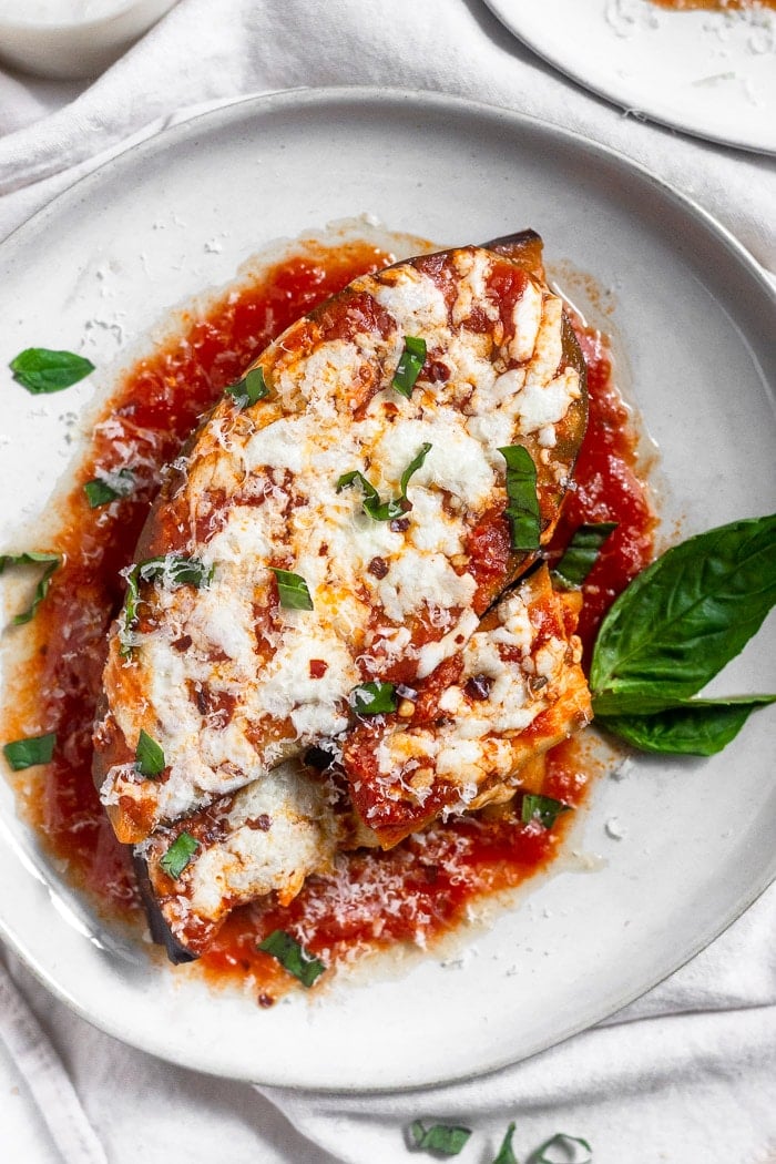 Overhead view of not breaded instant pot eggplant parmesan topped with fresh basil, parmesan cheese, and red pepper flakes.