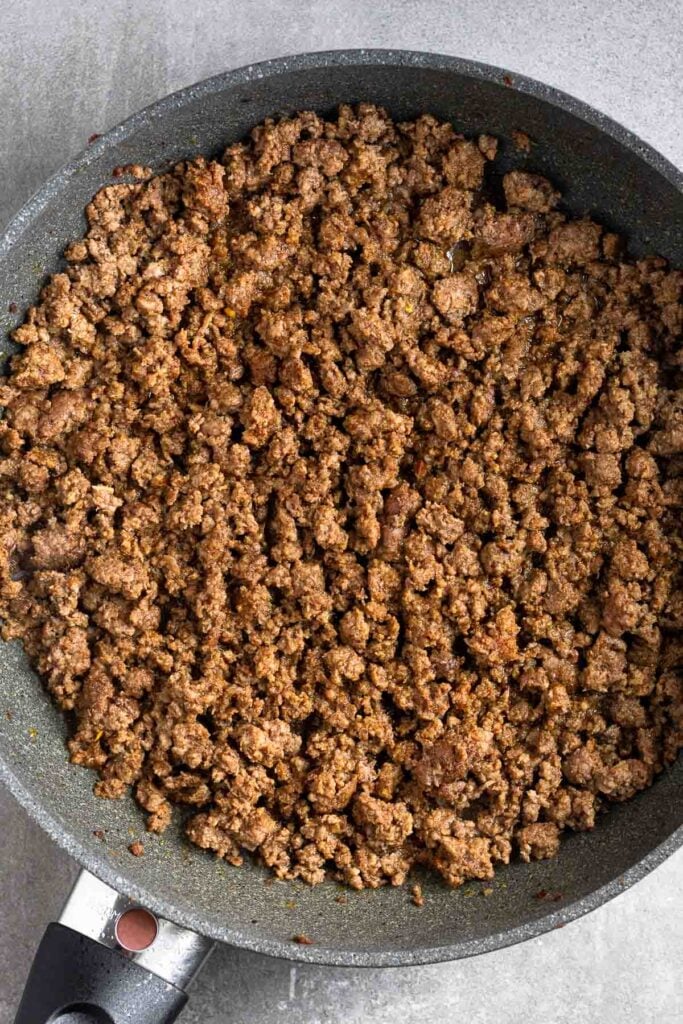 Large skillet of sautéed seasoned ground beef.