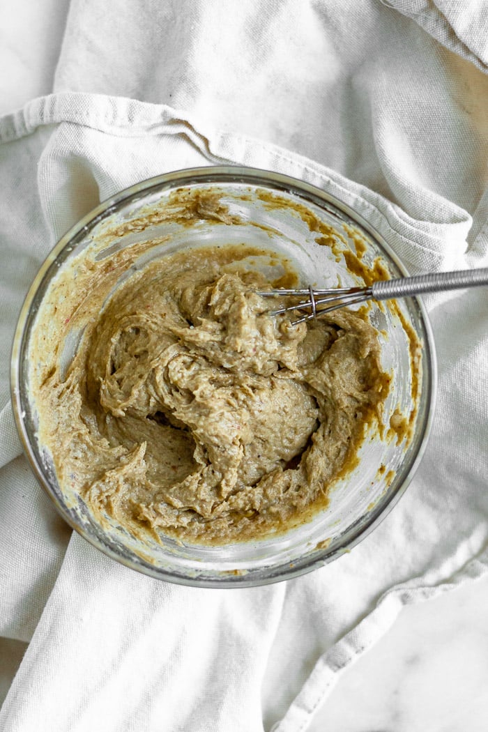 A small glass bowl of vanilla protein icing sitting on a tan towel.