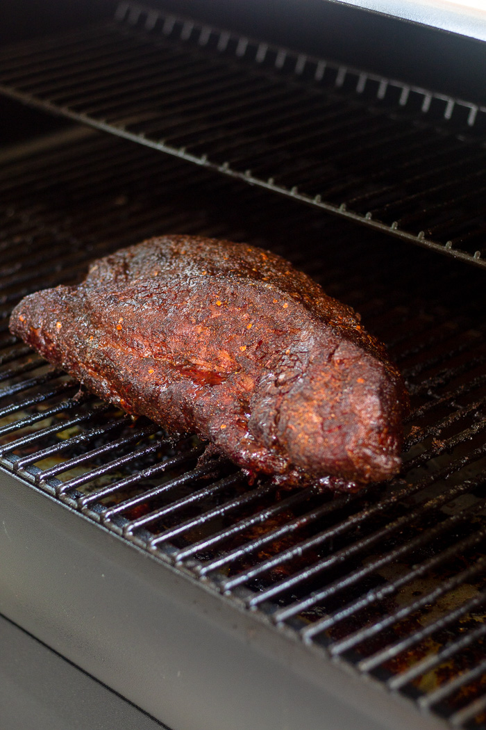 Large smoked brisket with dry rub sitting on a Traeger grill.