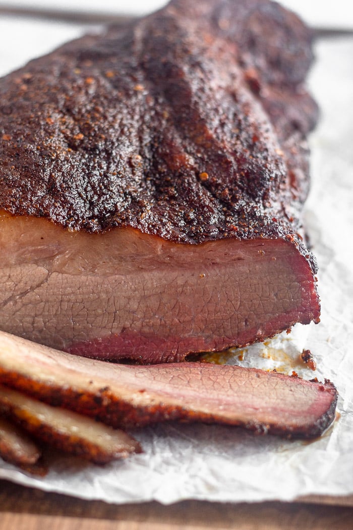 Close up of smoked brisket with dry rub with a few pieces sliced off.