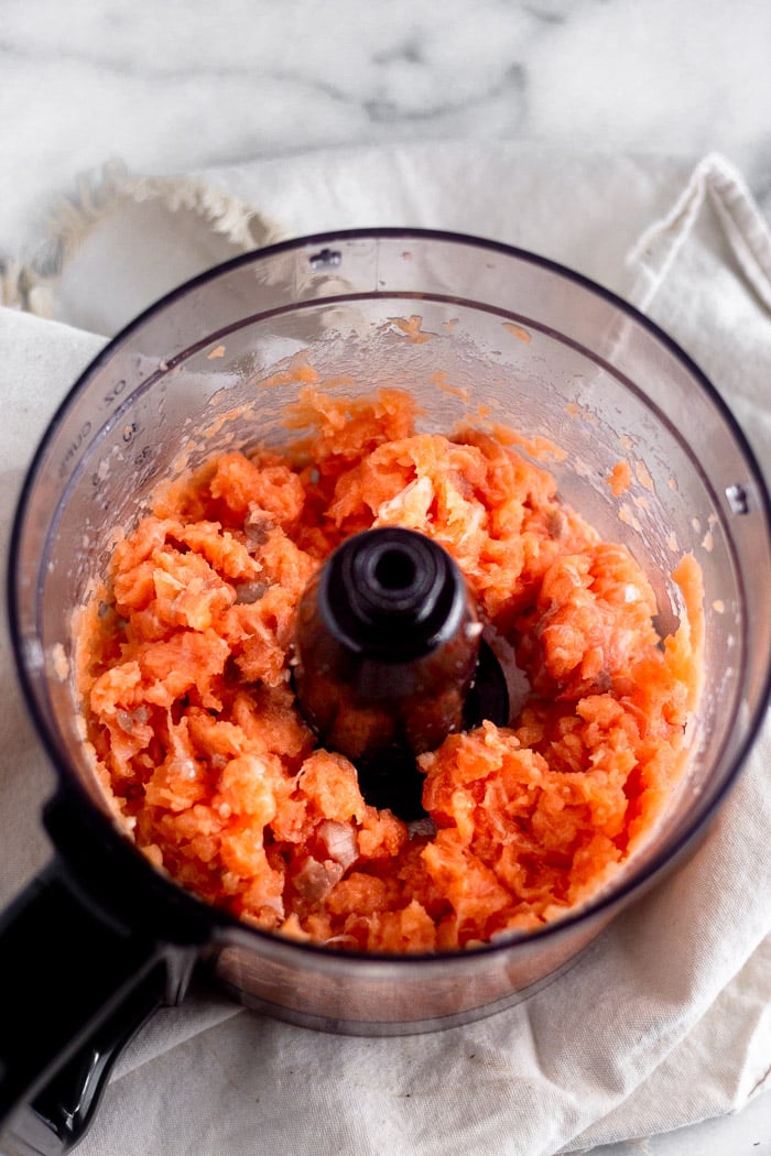 Raw salmon in a food processor that has been pulsed down to little pieces.