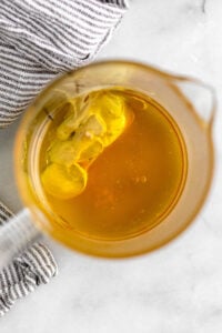 Measuring cups full of avocado oil, apple cider vinegar, dijon mustard, honey, and salt.