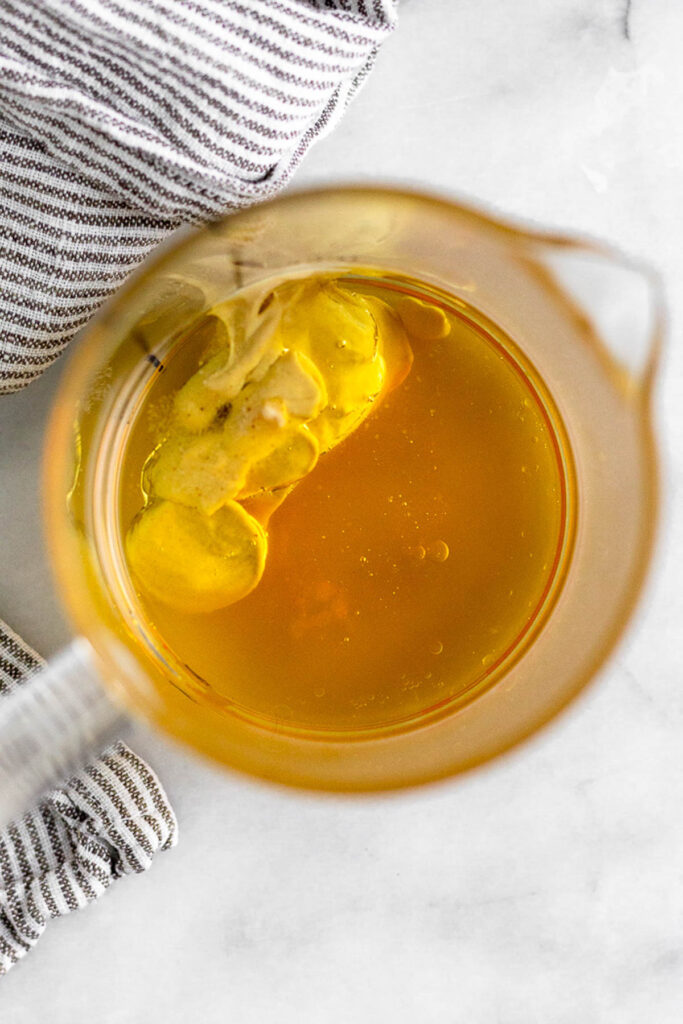 Measuring cups full of avocado oil, apple cider vinegar, dijon mustard, honey, and salt.