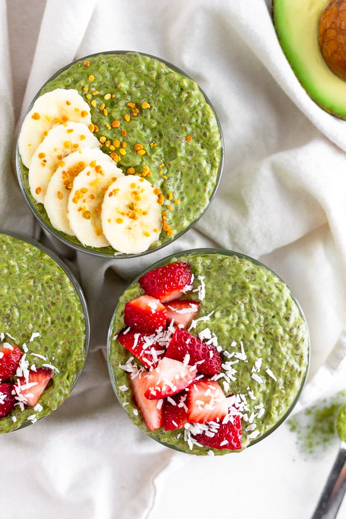 Overhead shot of matcha chia pudding topped with fresh strawberries and bananas sitting on a white towel.